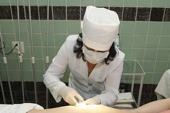 Медсестра сосет двум пациентам через специальные дырки в стене
